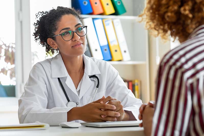 A person in a white coat talking to a patient