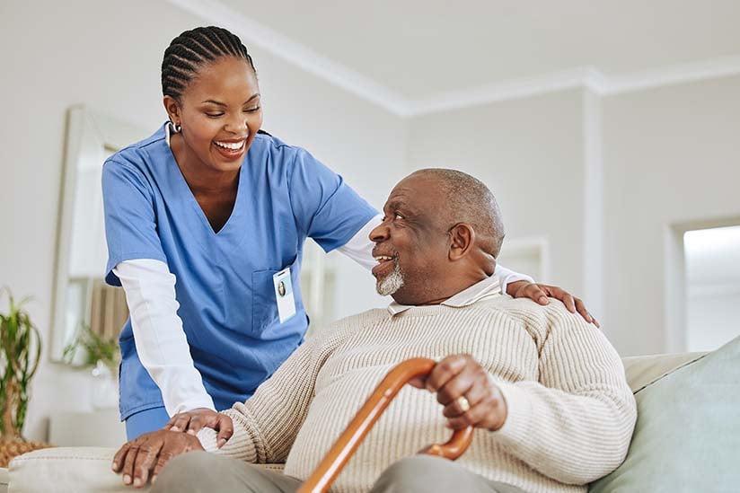 Nurse helps older man with cane