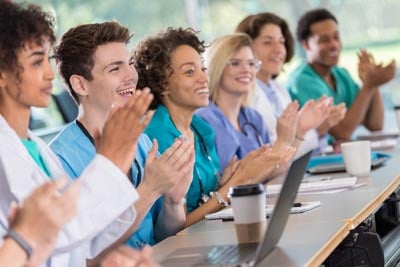 Diverse group of medical students applaud professor