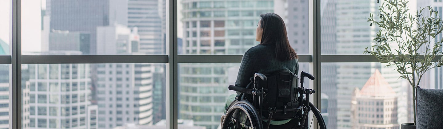 Disabled woman in wheelchair enjoying the view from her high rise apartment